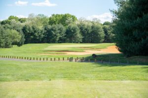 Lush green golf course at Bella Vista Country Club featuring manicured fairways and a sand trap, ideal for elegant gatherings and events.